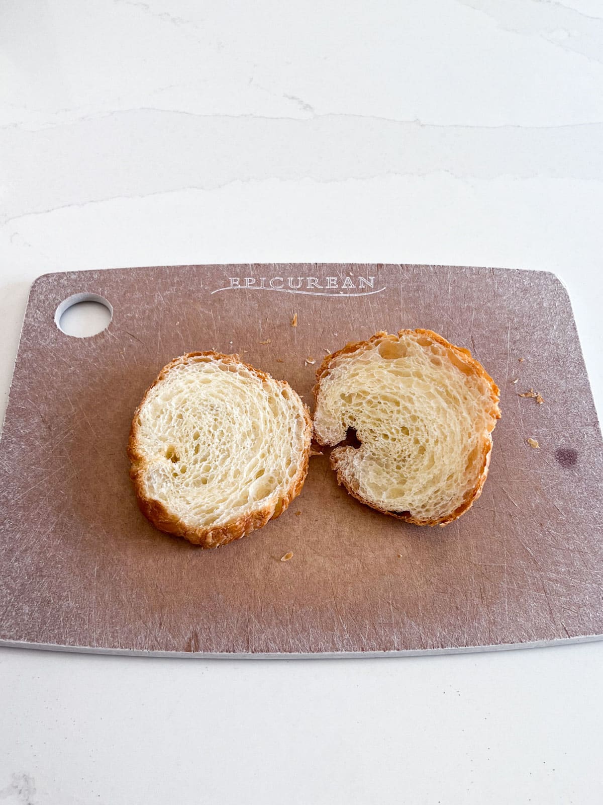 A croissant cut in half on a cutting board.