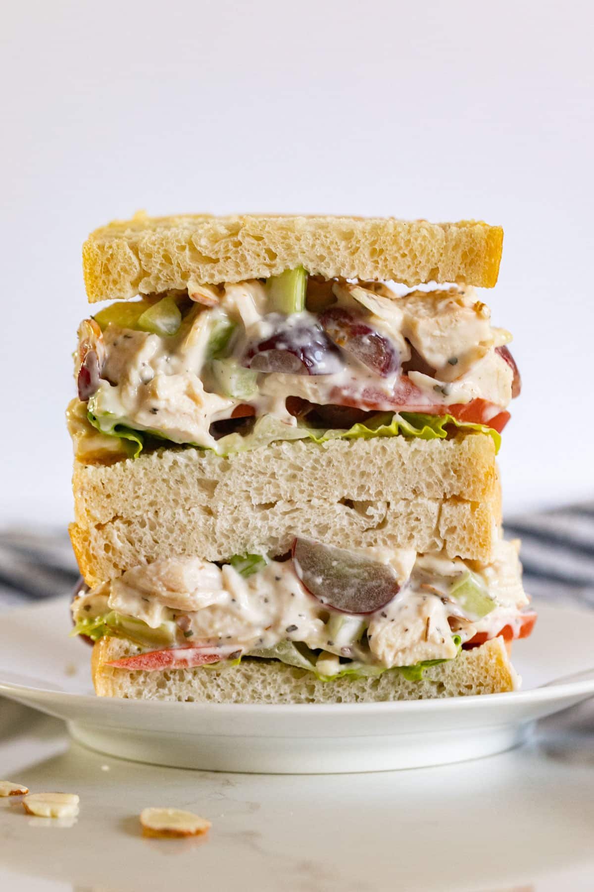 Two halves of a chicken salad sandwich piled on top of each other revealing the inside of the sandwich.