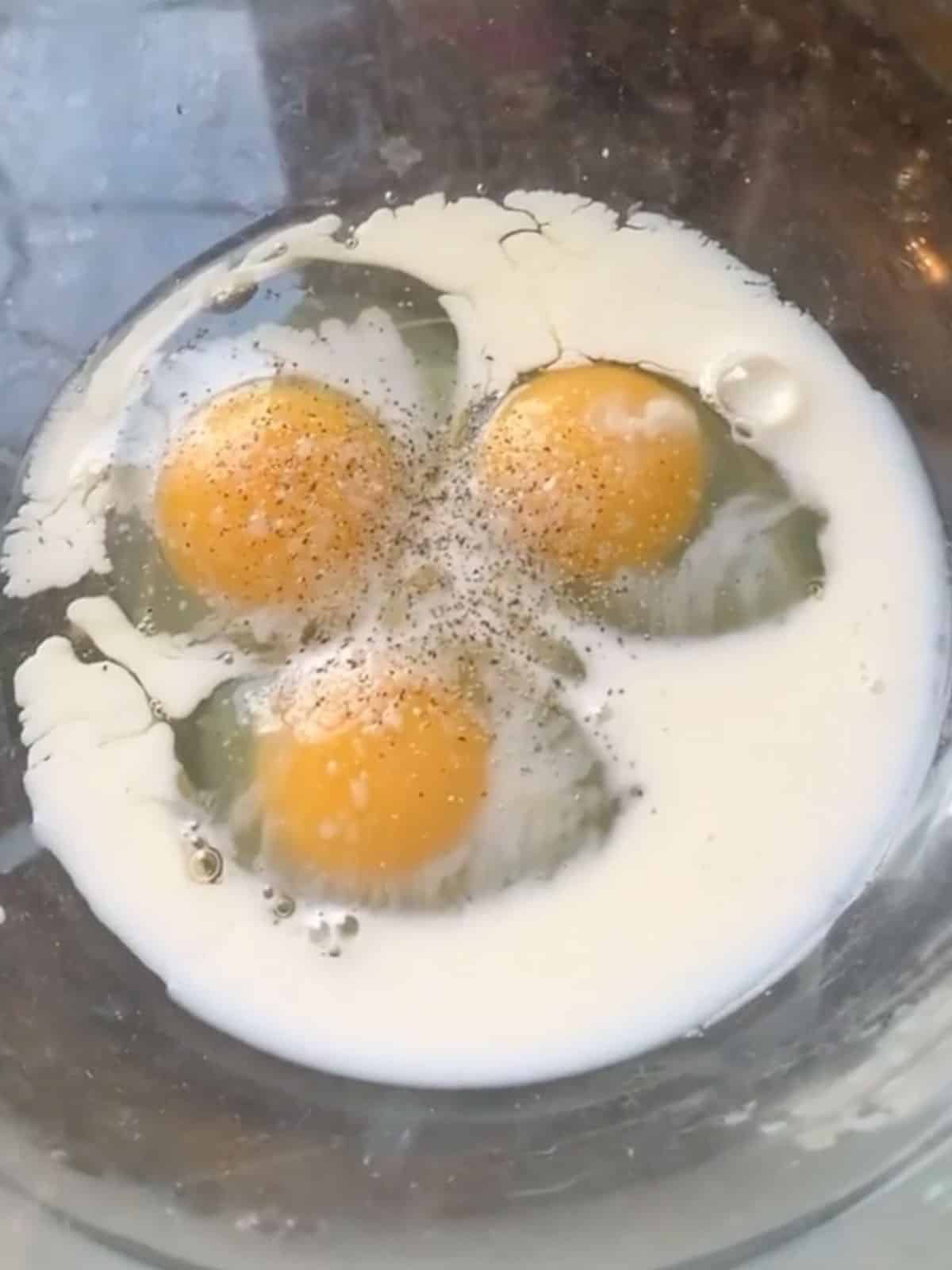 Eggs, milk and seasonings in a glass bowl.