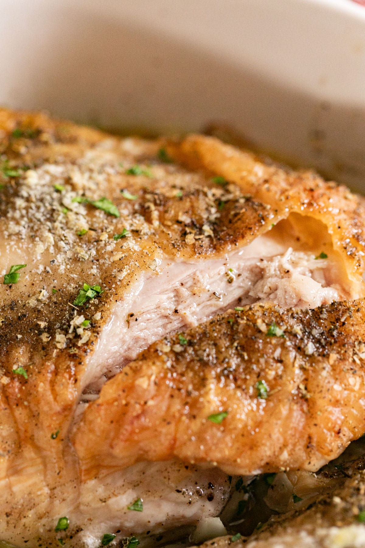 A close up image of the top of a turkey thigh cut into exposing the juicy, perfectly cooked meat inside.