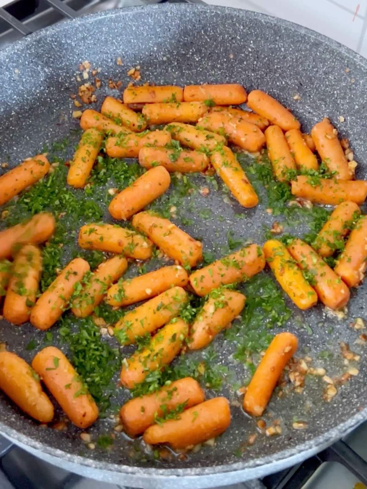 Parsley being sprinkled over the cooked carrots.