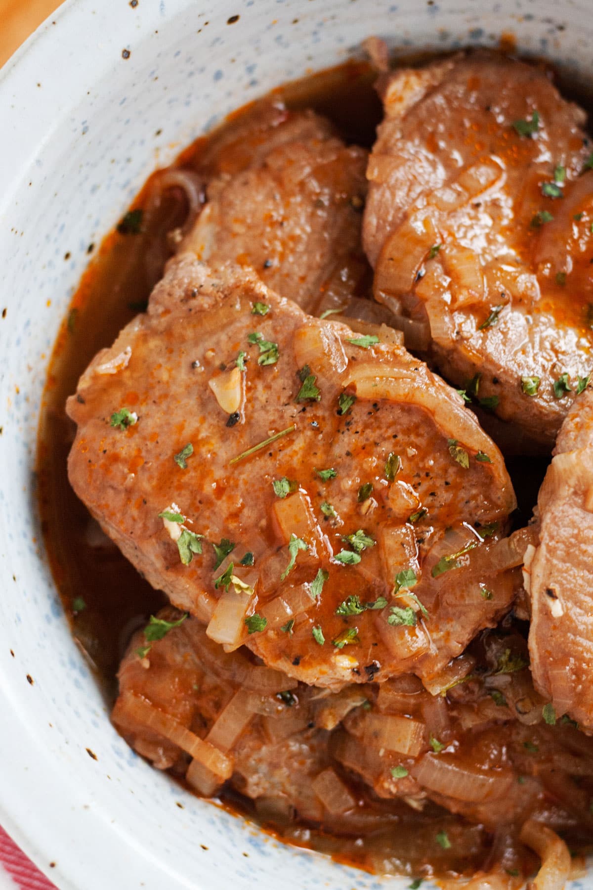 An overhead close up image of pork chops in an onion wine sauce.