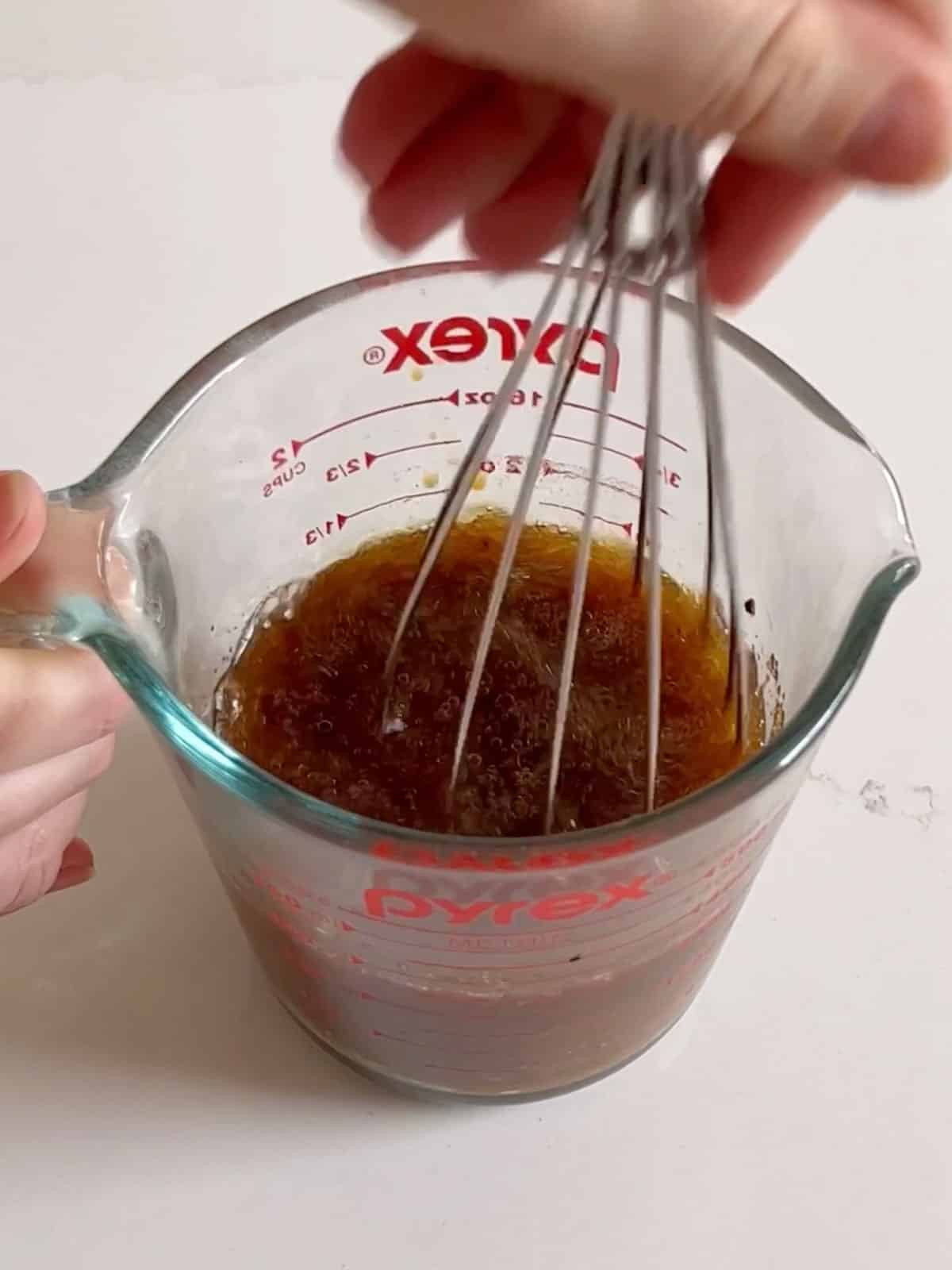 Marinade being whisked together in a liquid measuring cup.