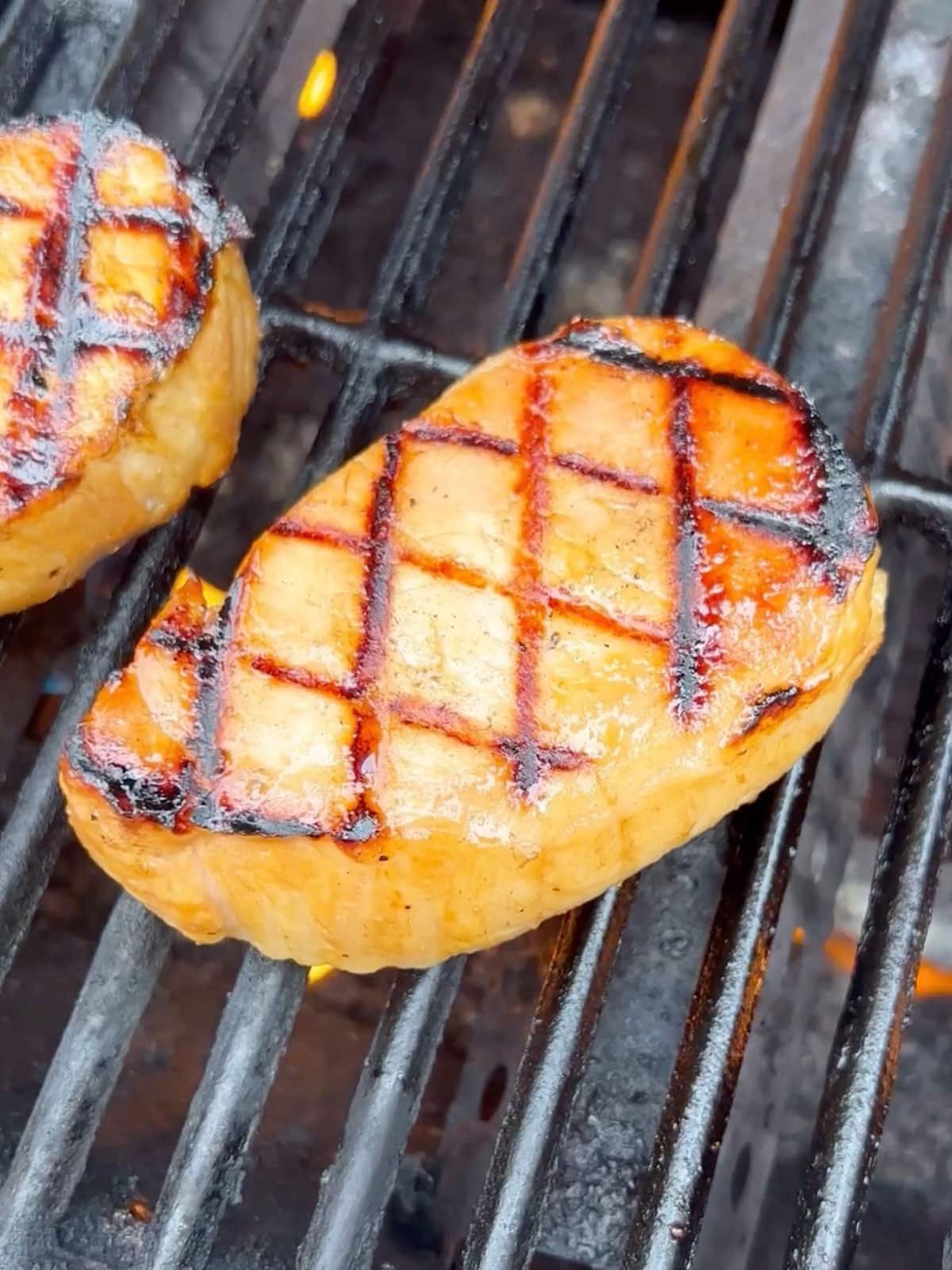 A pork chop cooking on the grill.