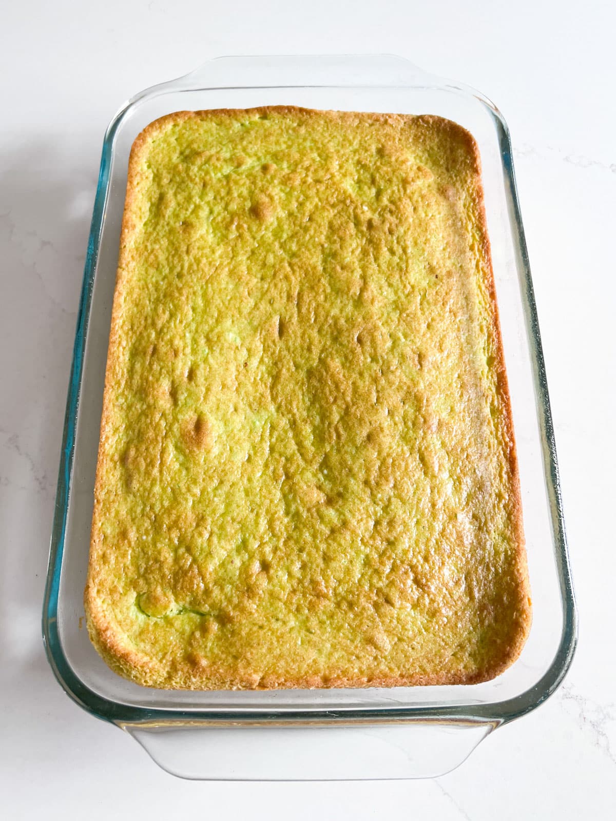 The baked and cooked cake in a rectangular glass pan.