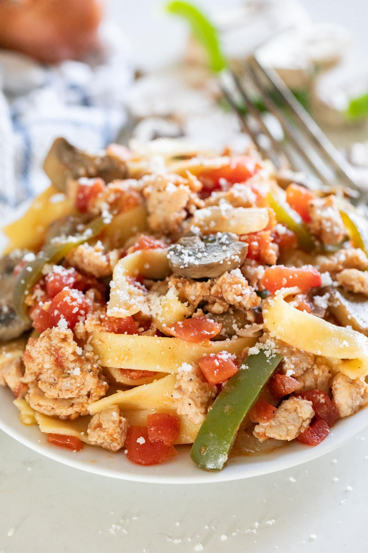 A close up of a bowl of pasta with sausage and peppers.