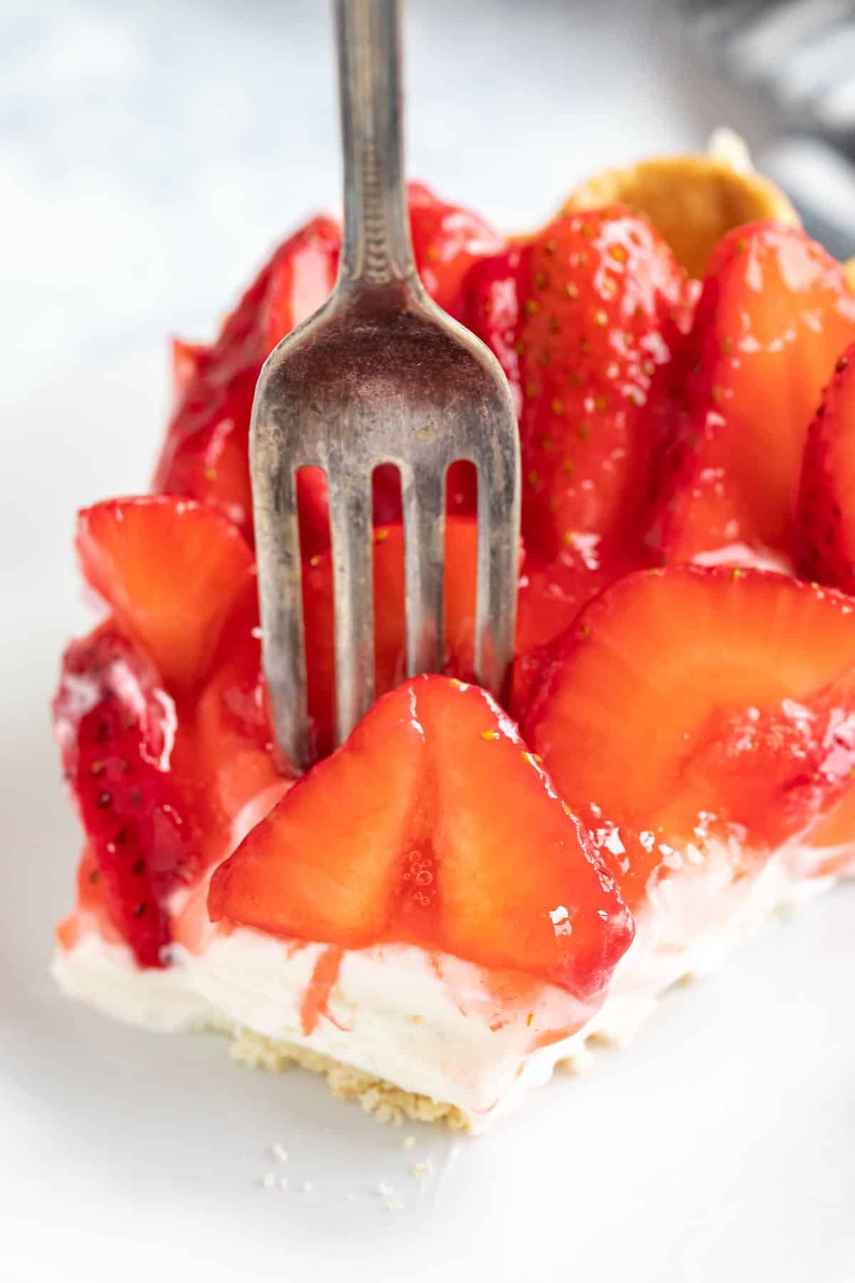A close up image of a fork piercing into the strawberry pie with cream cheese.