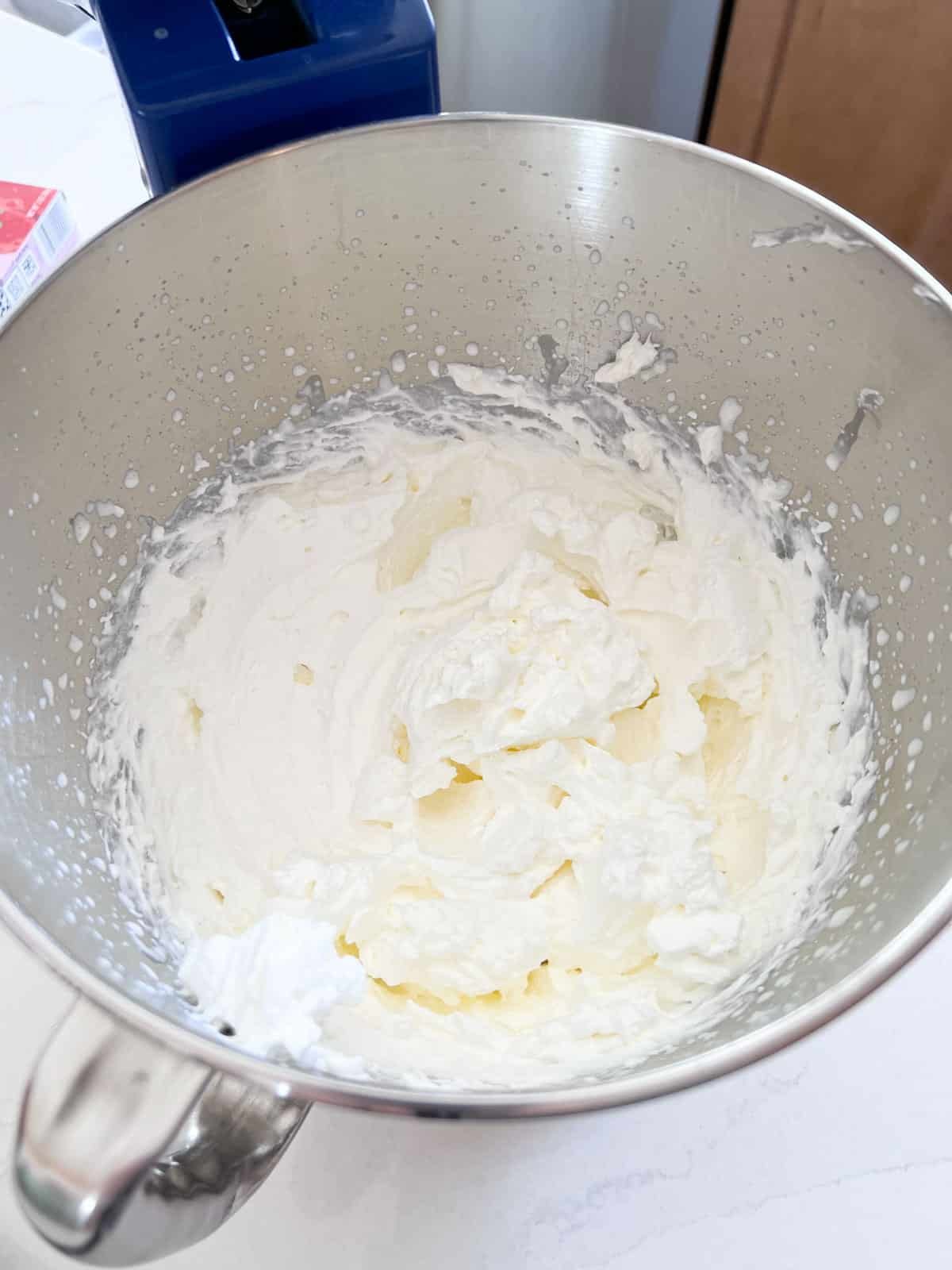 Whipped cream in a stand mixer bowl after being whipped in to stiff peaks.