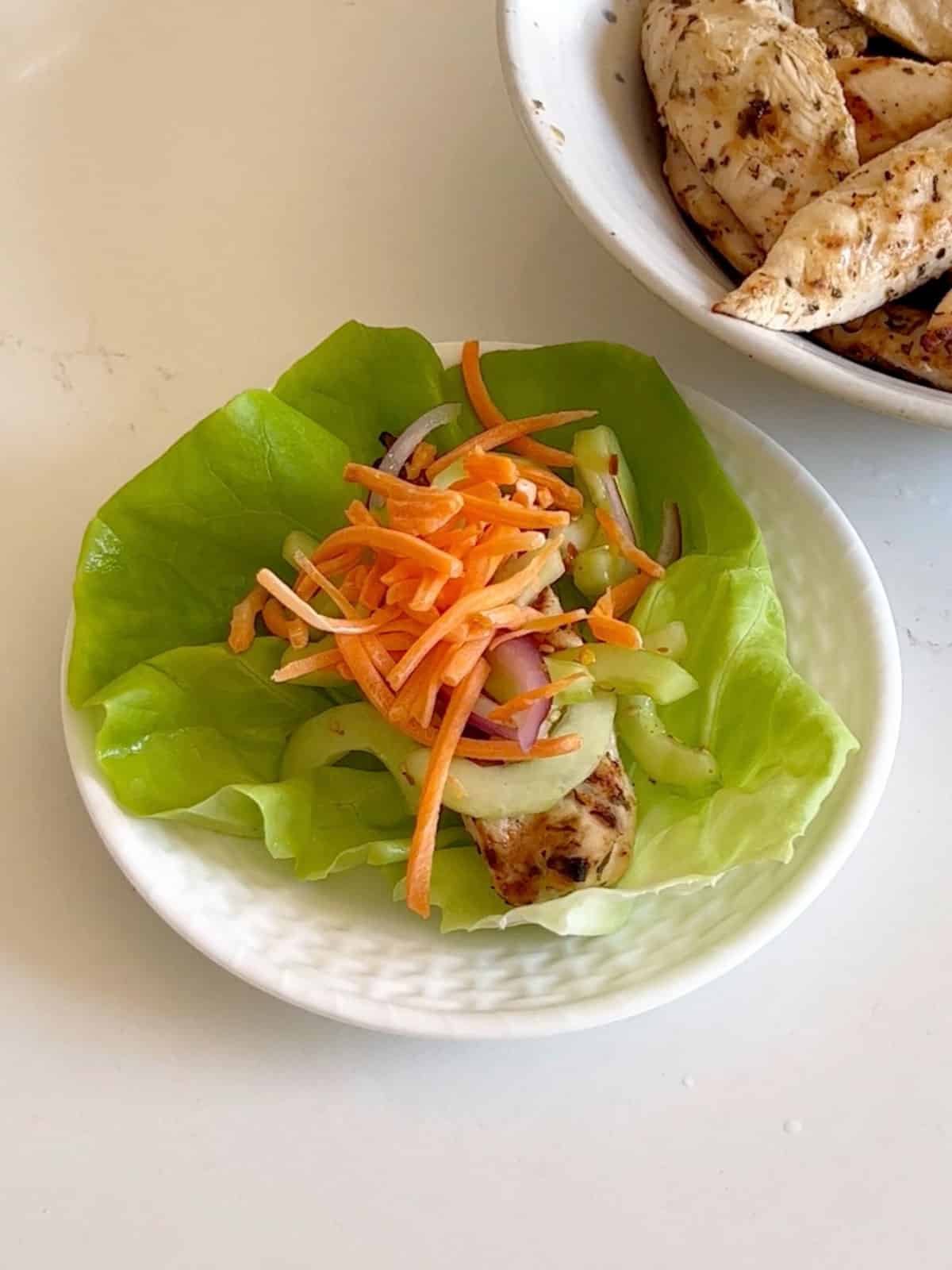 Toppings on the chicken lettuce wrap on a white plate.