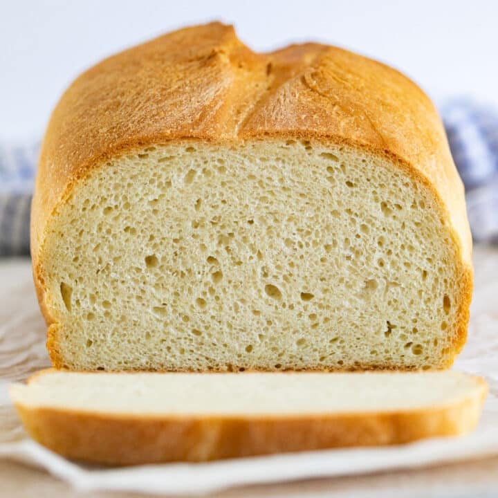 A straight on image of a loaf of bread with a slice cut off exposing the inside of the bread.