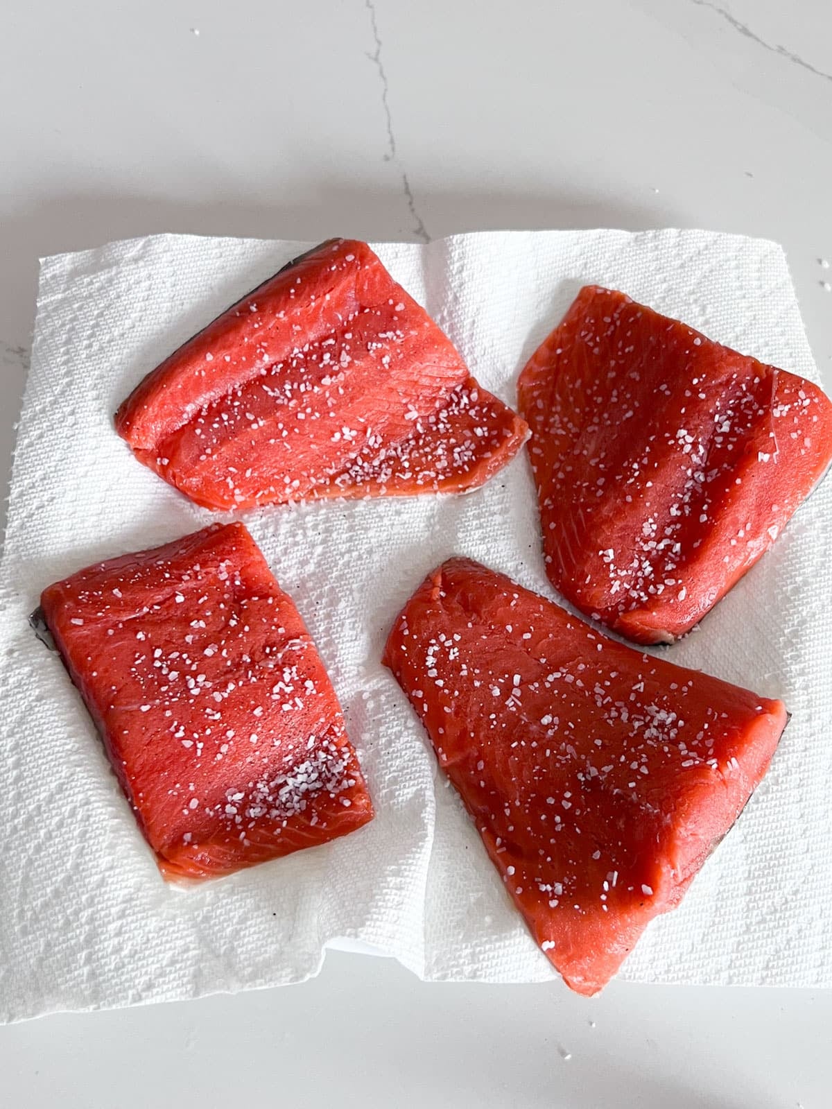Salmon filets with salt and pepper on them.