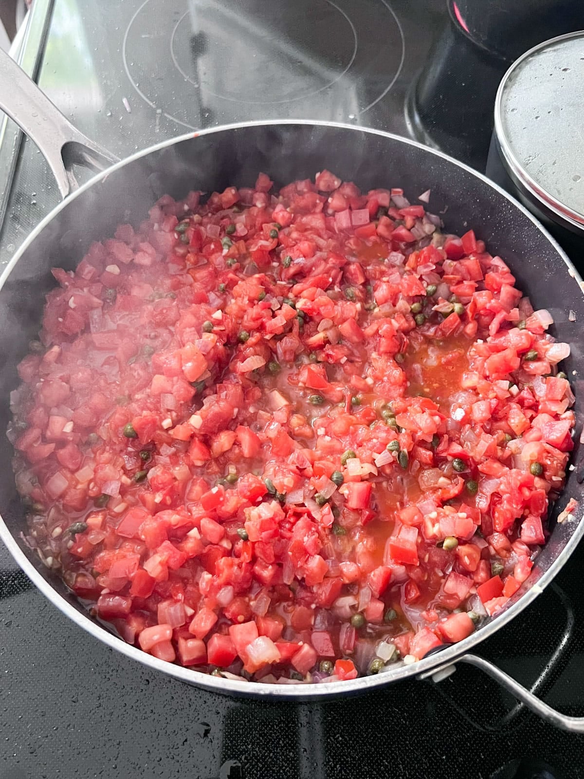 Tomatoes added to the onion mixture in the pan.