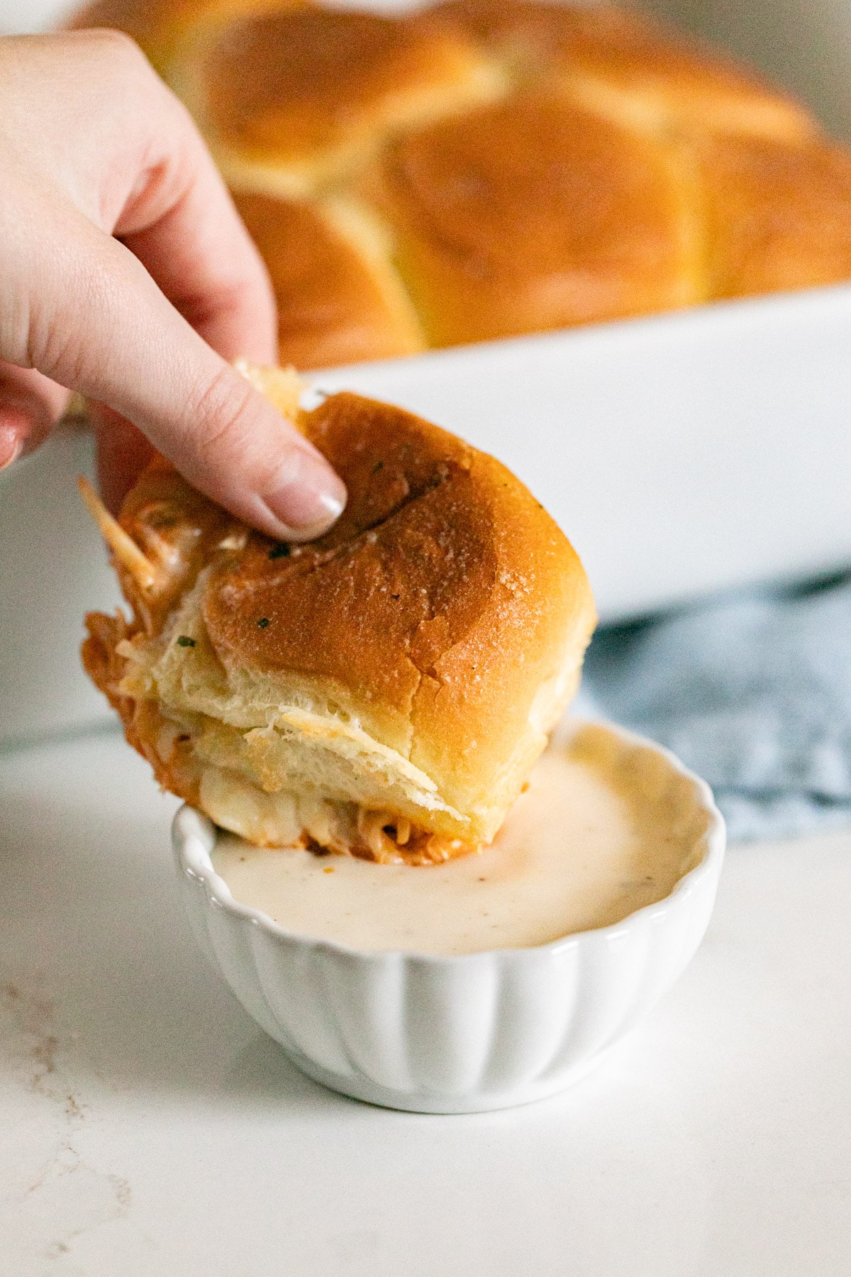 A buffalo wing slider being dipped in a bowl of ranch dressing.