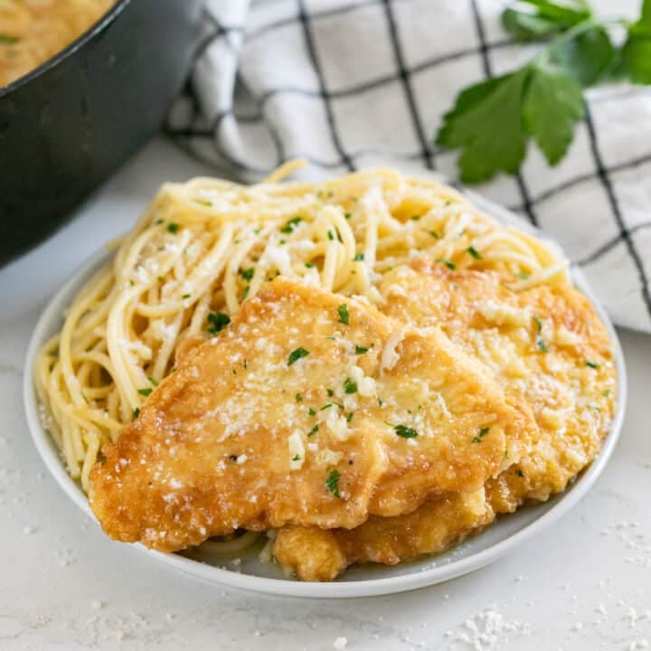 Chicken french on a plate with spaghetti.