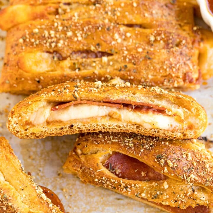 A close up image of the side of a slice of pizza bread revealing the melty cheese and pepperoni inside, on top of the rest of the pizza roll.