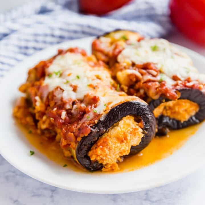 Two pieces of eggplant rollatini on white plate.