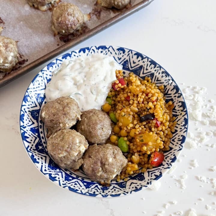 A bowl of lamb meatballs with tzatziki and couscous.