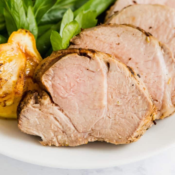 A close up image of sliced pork on a plate with green beans.