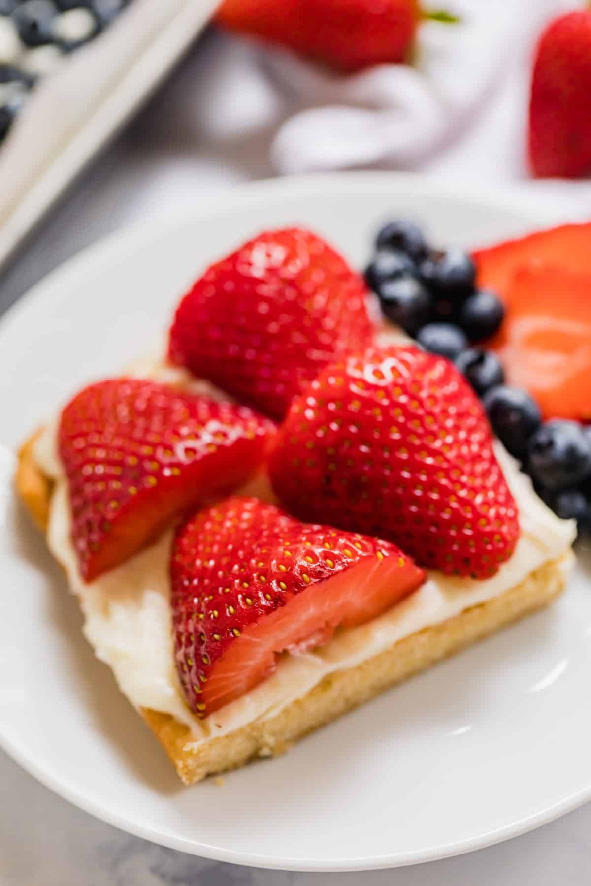 A close up image of a slice of flag fruit pizza on a plate.