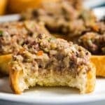 A close up of a baguette slice with olive spread on it and a bite taken out of it.
