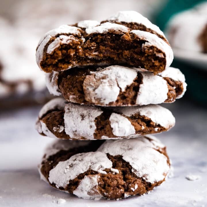 A stack of crinkle chocolate cookies with a bite taken out of the top cookie.