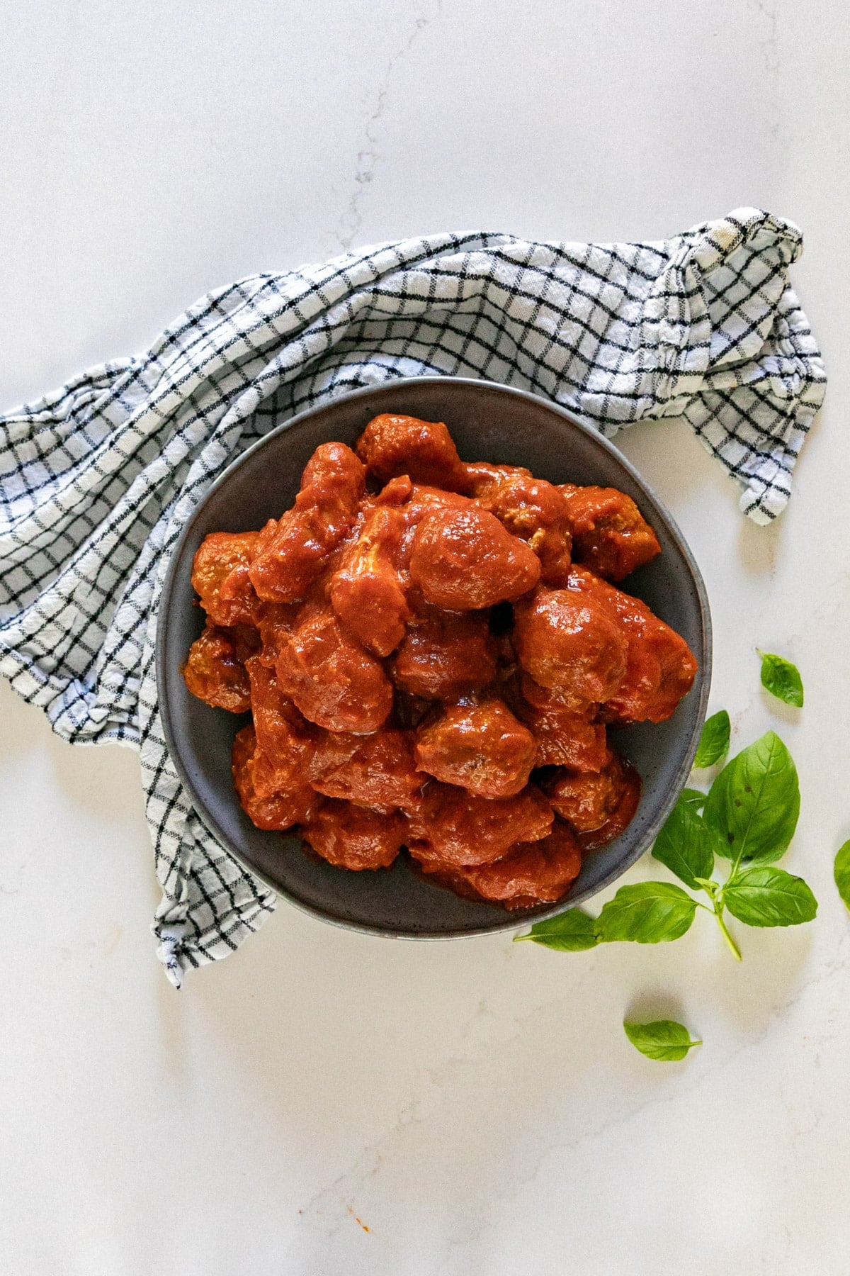 An overhead image of a bowl of meatballs and pork in sauce.