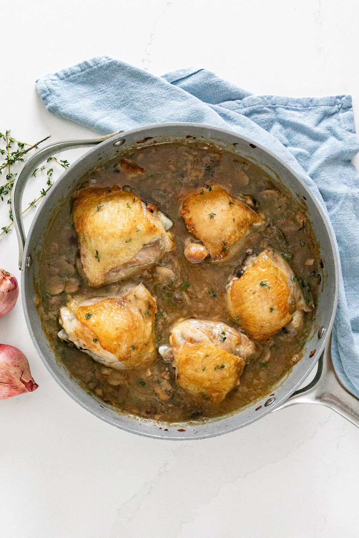 An overhead images of chicken thighs and gravy in a pan.