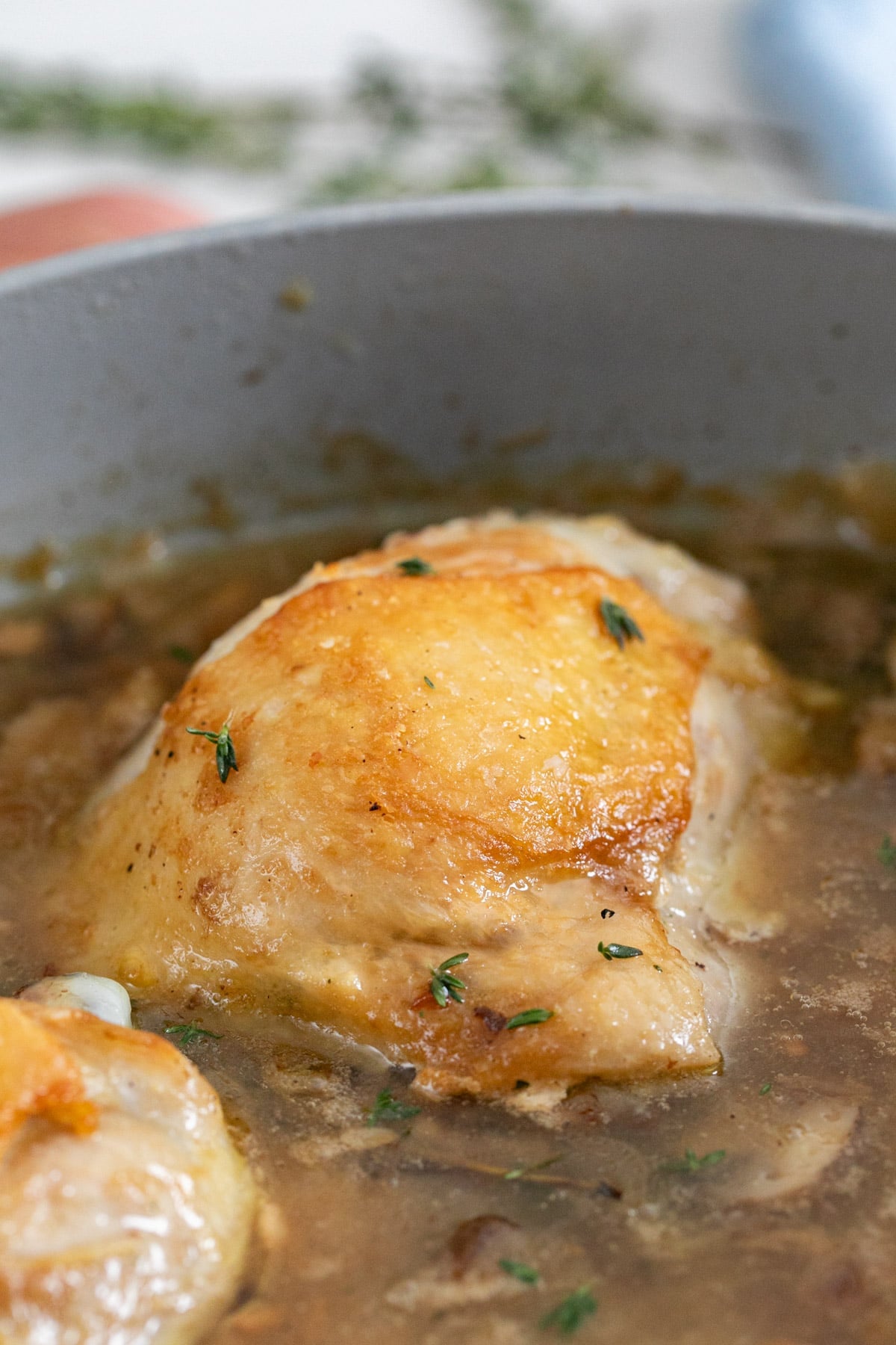 A close up image of a golden chicken thigh in champagne sauce.