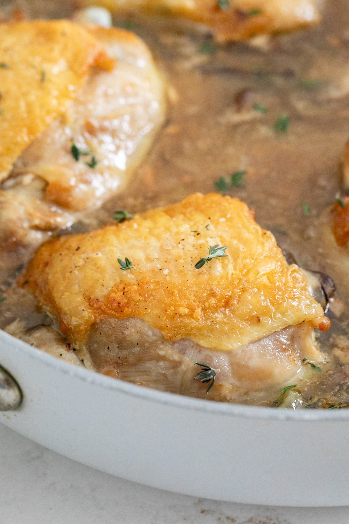 A close up image of a chicken thigh in the pan.