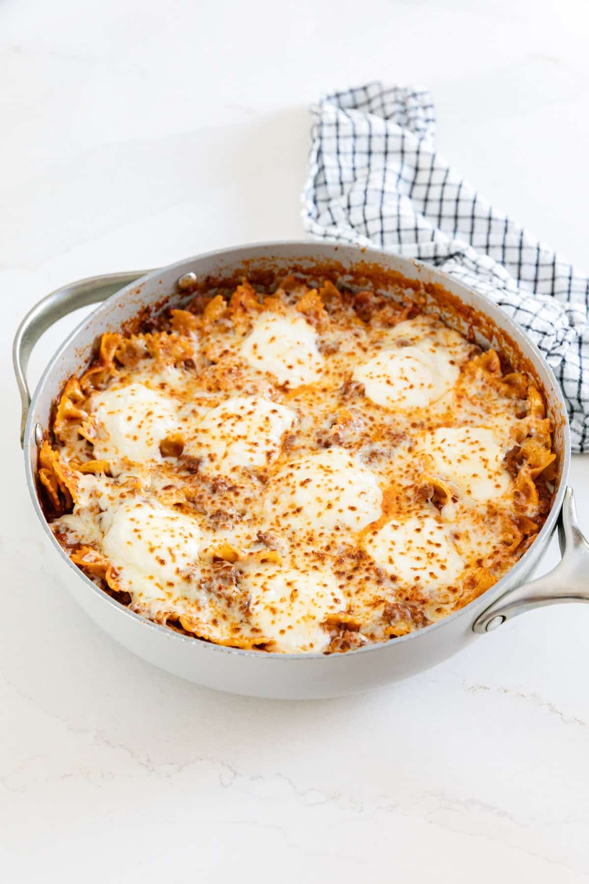 A pan of lasagna skillet with a striped towel behind it.
