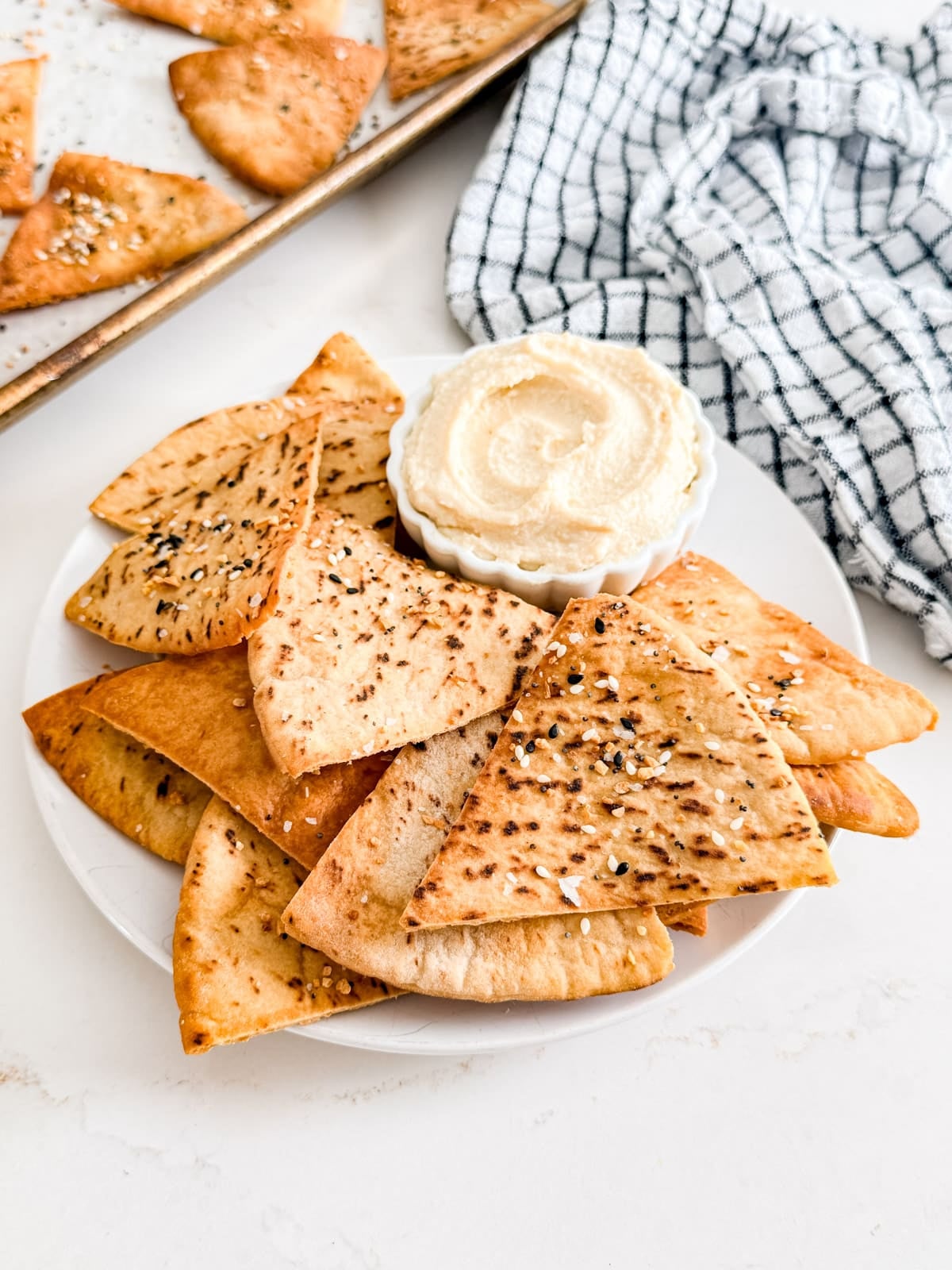 A plate of pita chips with a bowl of hummus on it.