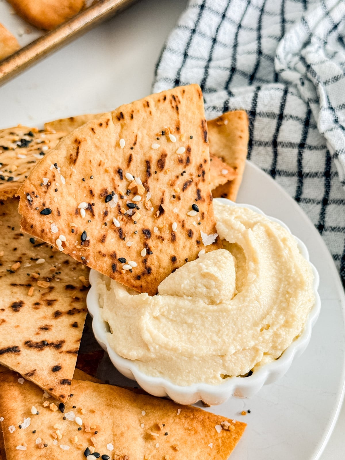A close up image of a pita chip in a bowl of hummus.