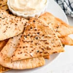 A close up of a pita chip onto top of other pita chips.