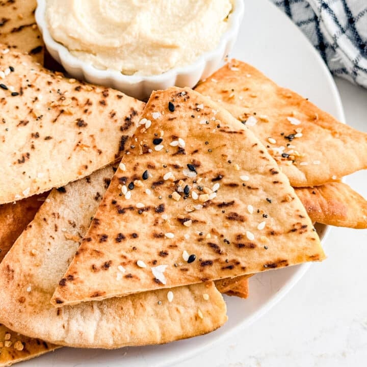 A close up of a pita chip onto top of other pita chips.