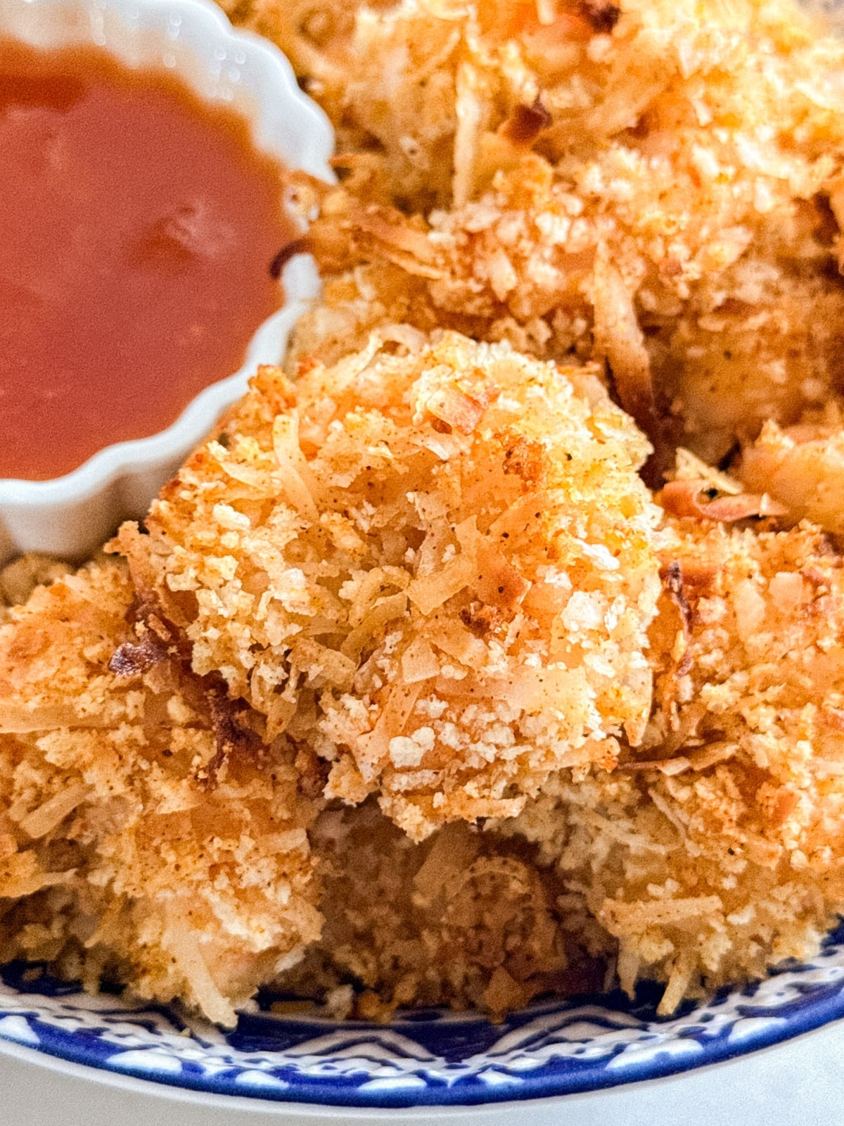 A close up image of a piece of coconut shrimp on top of others.