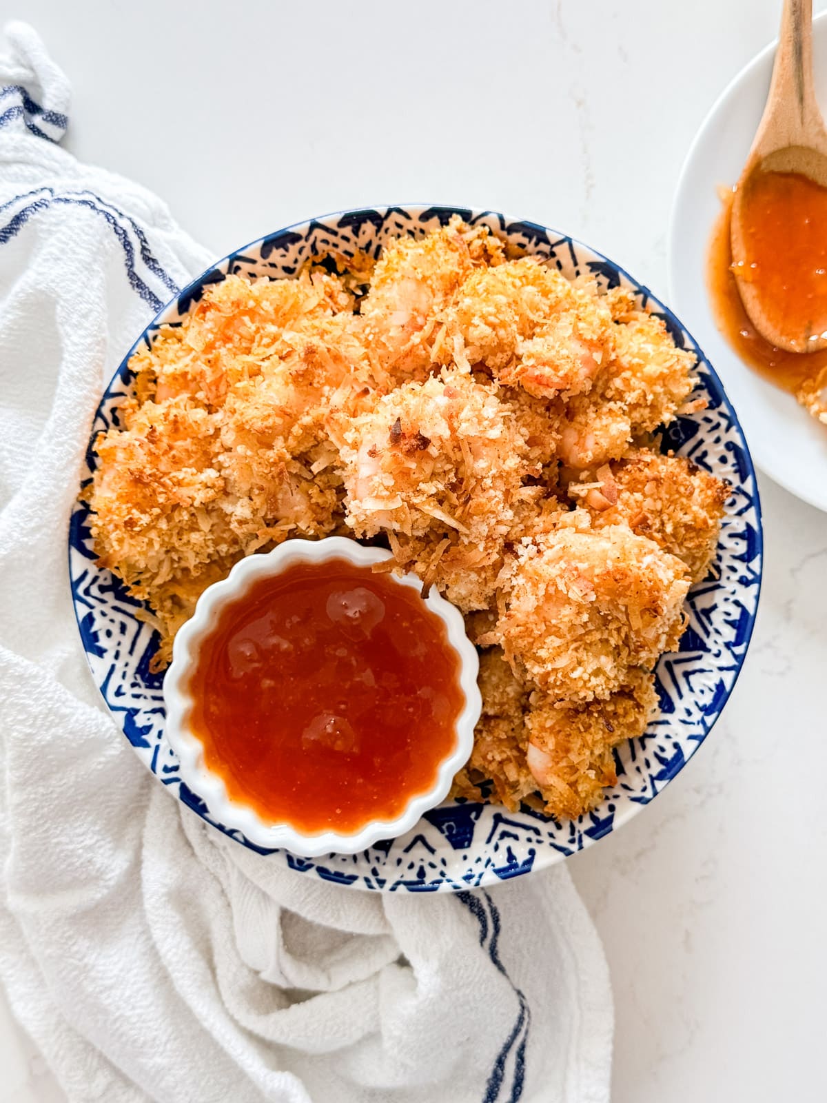 An overhead image of a bowl of coconut shrimp with apricot sauce.