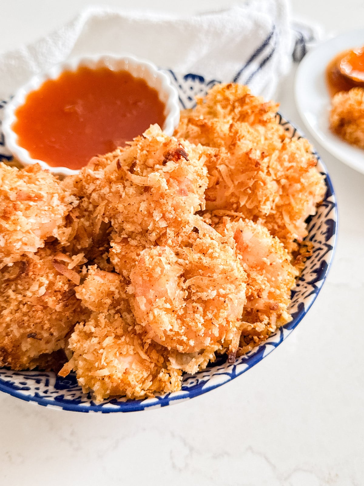 A bowl of coconut shrimp and sauce.