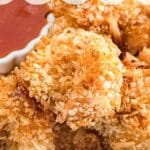 A close up image of a piece of coconut shrimp on top of others.