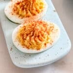 A close up image of a devil egg lined up on the end of a long plate with others behind it.