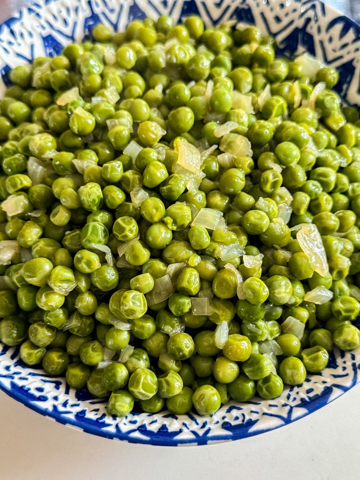 A close up image of peas and onions in a bowl.