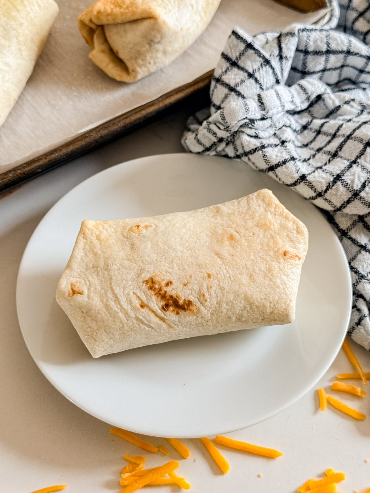 A bean burrito on a white plate.