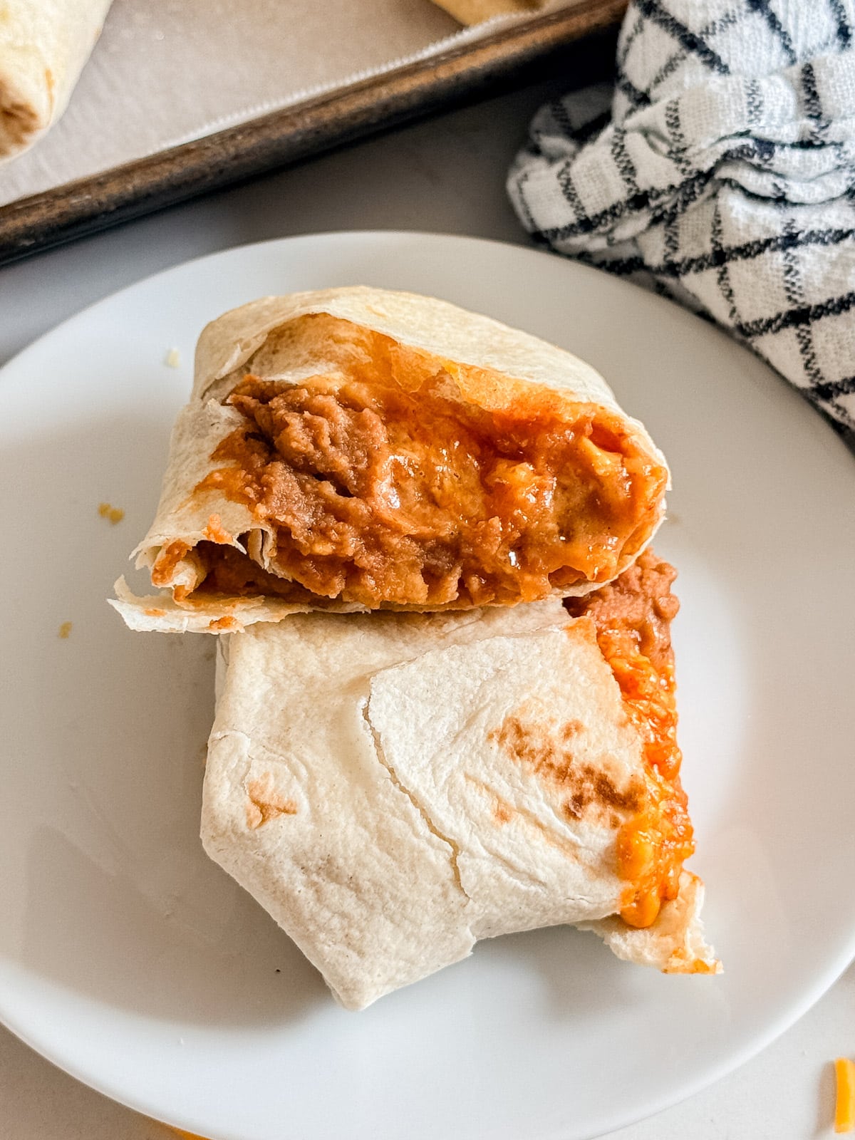 A bean burrito cut in half revealing the cheese and refried beans inside.
