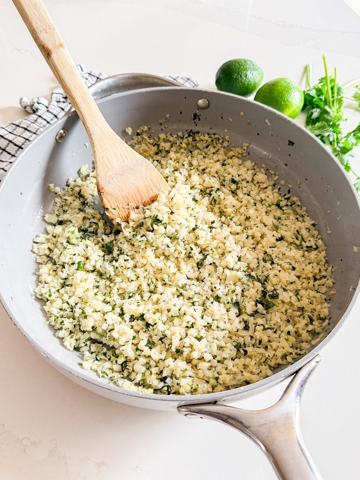 A pant of frozen cauliflower rice that's been cooked with a spoon in it.