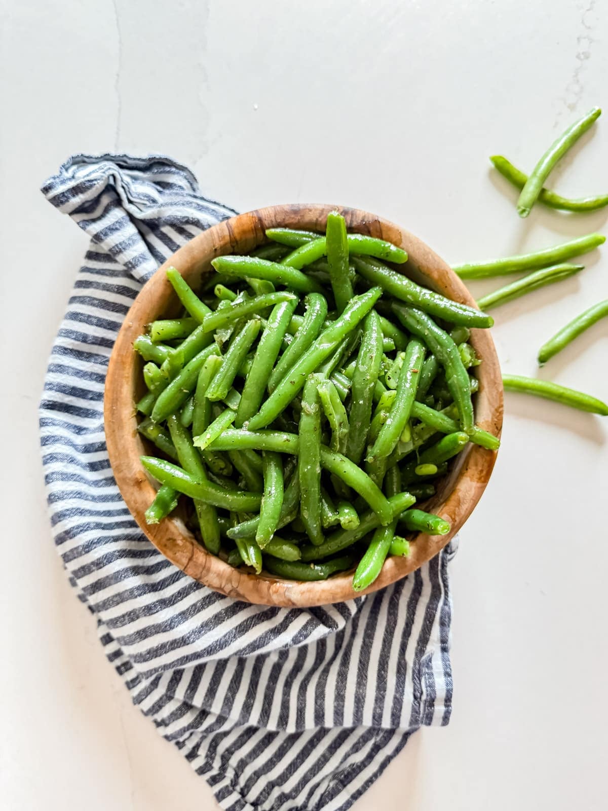 An overhead image of green bean salad in a wooden bowl.