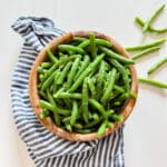 An overhead image of green bean salad in a wooden bowl.