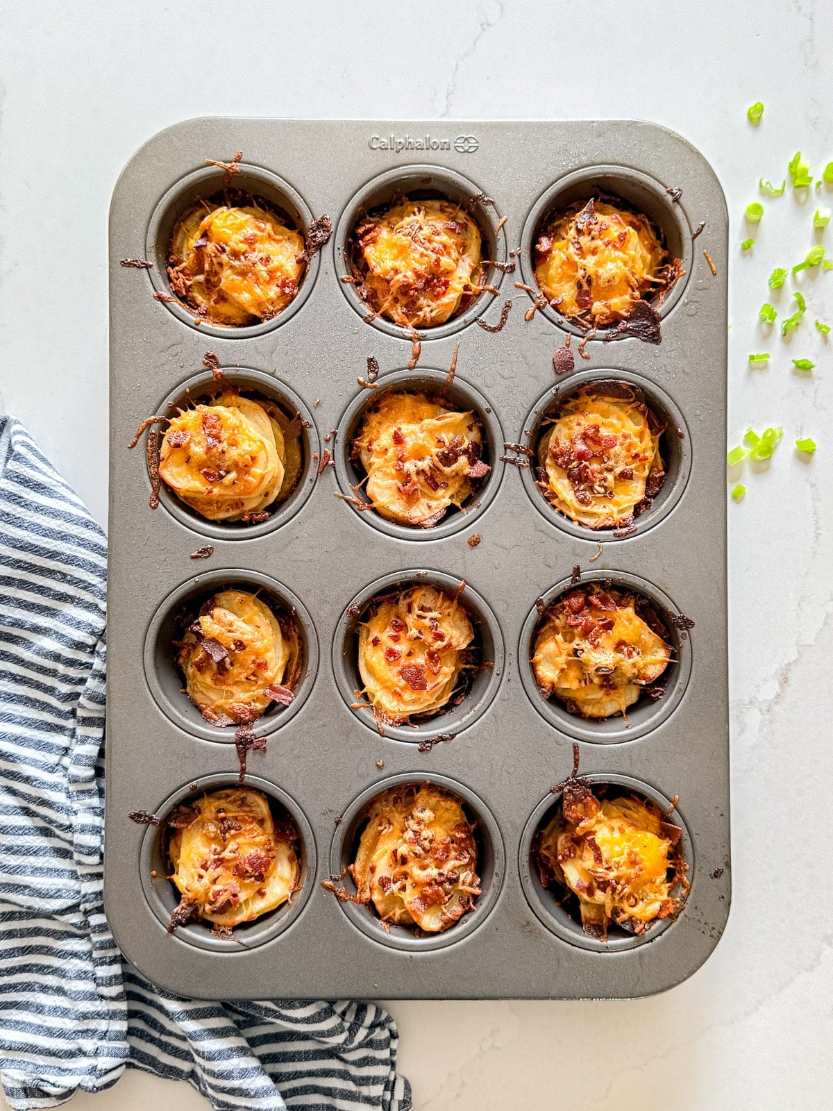 An overhead image of a muffin pan full of loaded potato stacks.