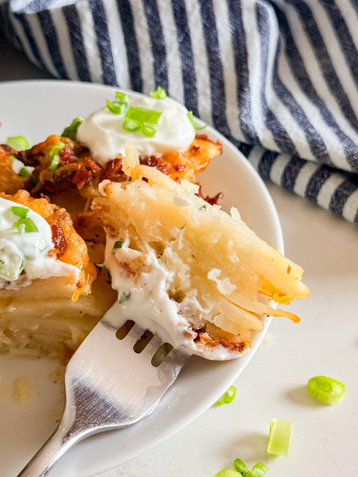 A bite of loaded potato stacks on a fork.