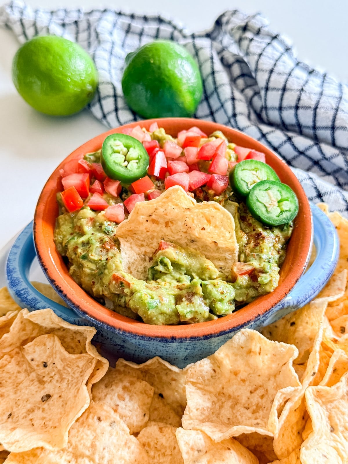 A bowl of guacamole with a chip in it.
