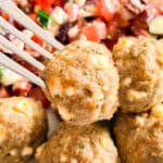 A close up of a fork holding a feta turkey meatball.
