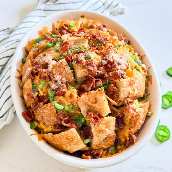 Popper pull-apart bread in a white pan surrounded by sliced jalapeños.